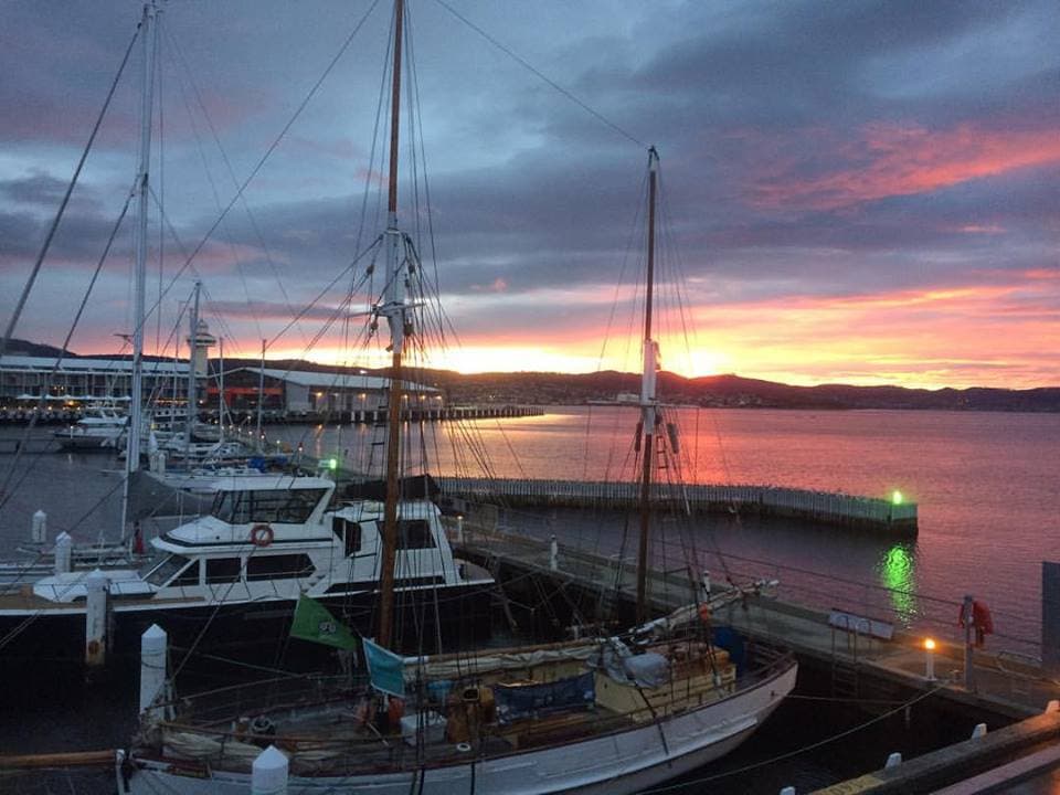 Yachts along the Hobart waterfront beneath a pink and gold sunset, from the travel journal